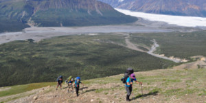 Backpackers hiking above an Alaska glacier with mountain views