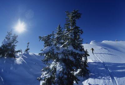Mountaineer ascending snowy peak in backcountry wilderness