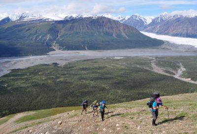 A group of backpackers trekking through rugged alpine scenery on the Donjek in the Canadian Yukon.