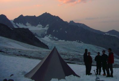 Backcountry mountaineering students camping on a glacier at sunset during an Alaska expedition.