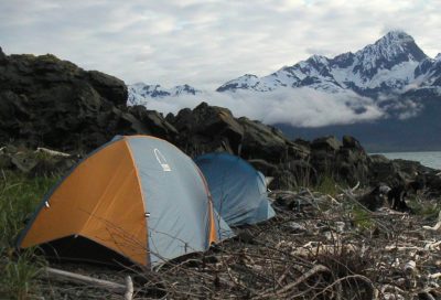 Backcountry sea kayaking expedition camp set along a rocky Alaskan shoreline.