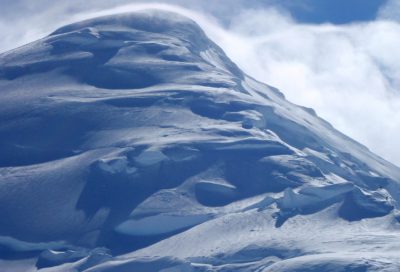 Wind-carved snow and steep glaciated slopes on Mt. Fairweather, a classic Alaskan mountaineering peak.