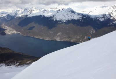 Backcountry skier carving fresh snow high above the fjords and mountains of Southeast Alaska.