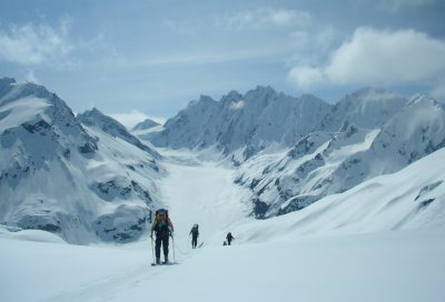 Backcountry mountaineers skiing across a high-alpine glacier during ski guide training in Alaska.