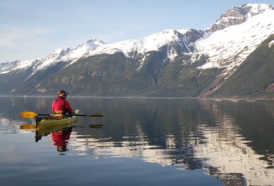 Scenic kayaking on Lynn Canal with glassy water and dramatic coastal mountains in Alaska.