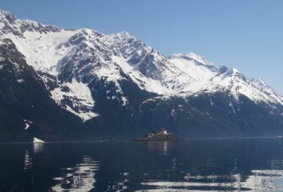 Group of sea kayakers paddling towards island lighthouse in Alaska
