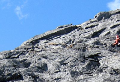 Alpine rock climber navigating rugged terrain on a guided climbing expedition.