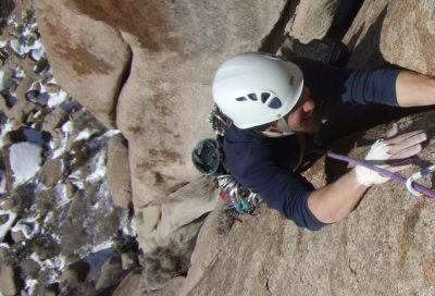 Trad climber placing gear and ascending a granite crack as part of climbing skills training.