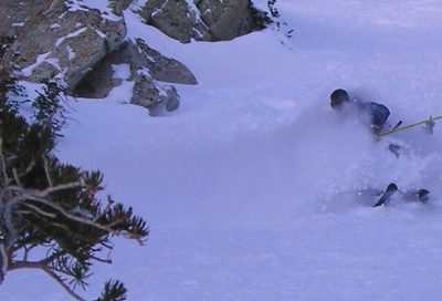 Skier in soft powder snow while skiing a steep Utah mountain slope.