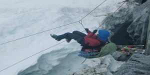 Mountaineer performing rope ascent drill over a glacier crevasse.