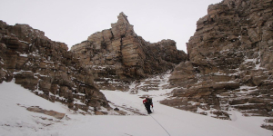 Mountaineer roped in while climbing a narrow snow-filled gully.