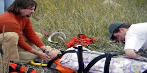 Wilderness first aid students securing a patient to a backboard.