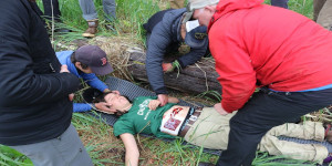 Wilderness first aid students assessing a patient during a medical training scenario.