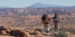 Two hikers trekking through red rock canyon country.
